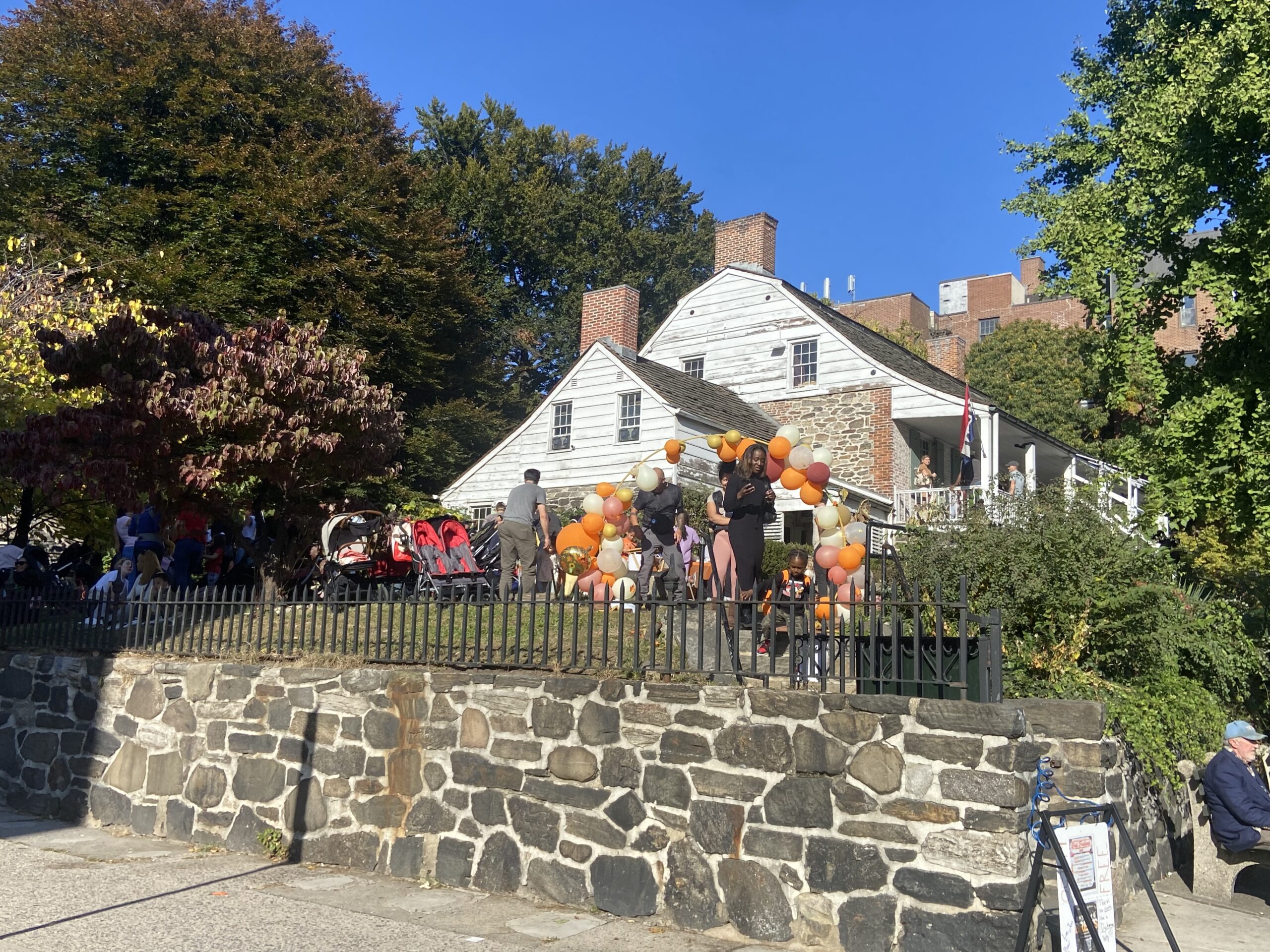 Una casa coloniale olandese in legno a due piani, con veranda e tetto spiovente, in piedi tra il verde in una giornata di sole, a Inwood, New York