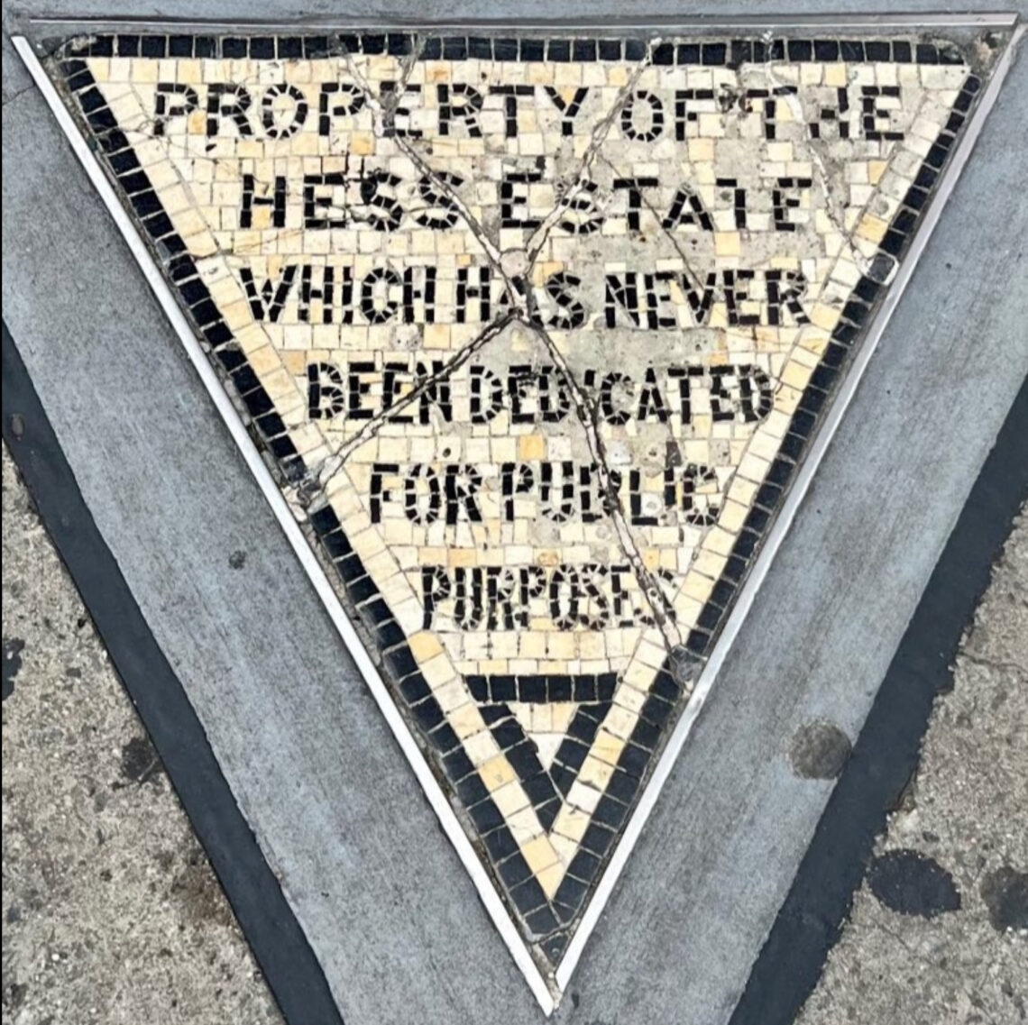 Il piccolo triangolo di mosaico del Hess Triangle incastonato nel marciapiede all'angolo tra Christopher Street e Seventh Avenue a Greenwich Village