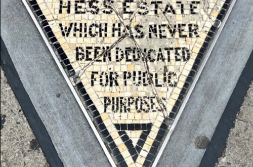 Il piccolo triangolo di mosaico del Hess Triangle incastonato nel marciapiede all'angolo tra Christopher Street e Seventh Avenue a Greenwich Village