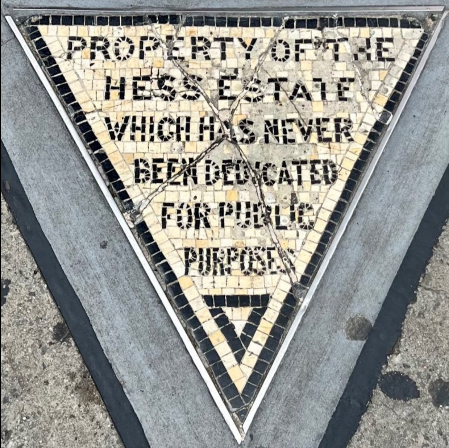Il piccolo triangolo di mosaico del Hess Triangle incastonato nel marciapiede all'angolo tra Christopher Street e Seventh Avenue a Greenwich Village