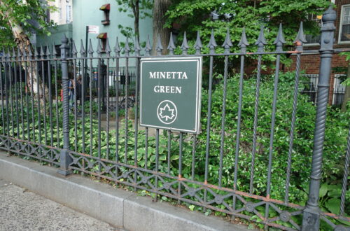 Un piccolo parco recintato con aiuole verdi e alberi, il Minetta Green, in una stradina del Greenwich Village a New York