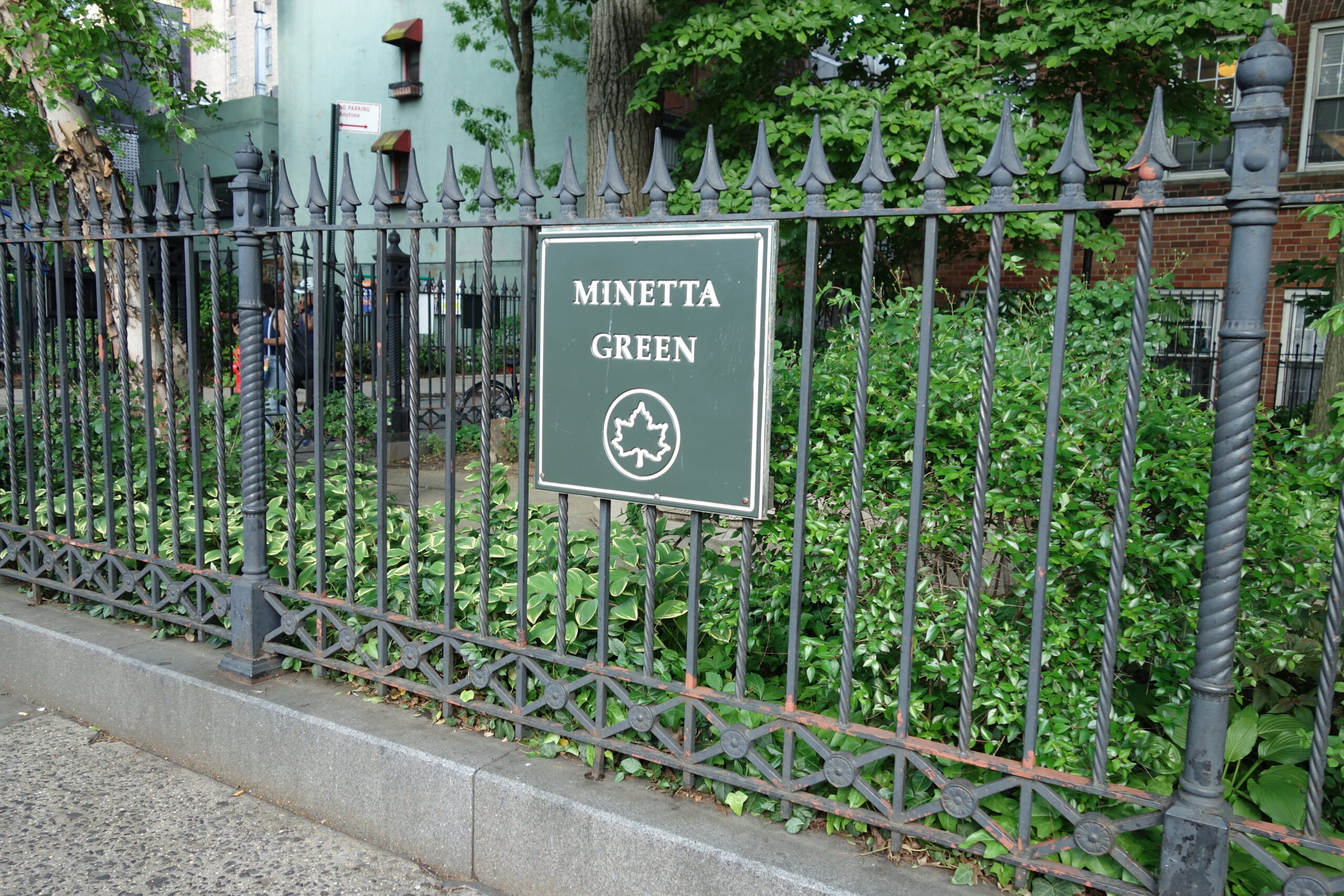 Un piccolo parco recintato con aiuole verdi e alberi, il Minetta Green, in una stradina del Greenwich Village a New York